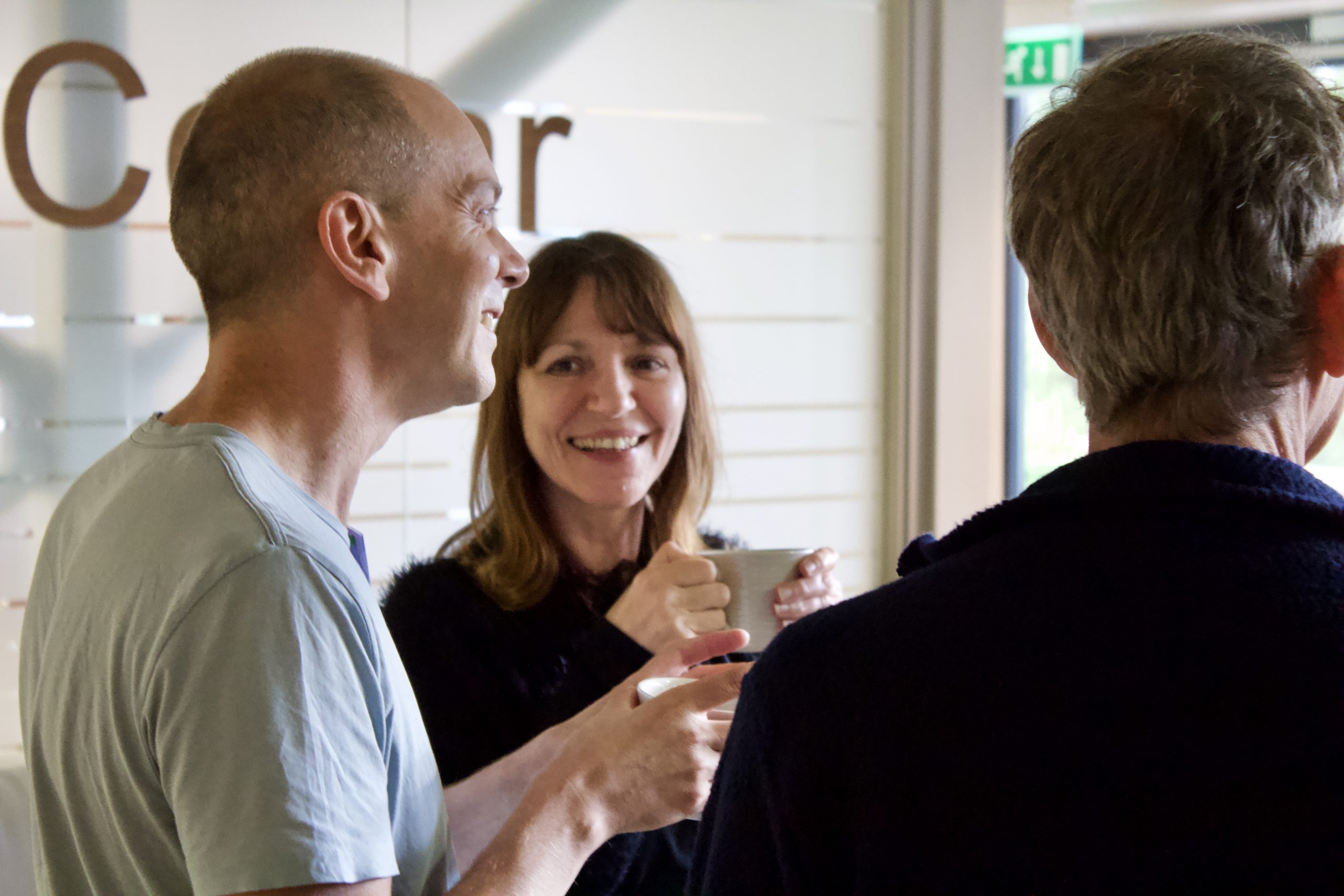 Three people smiling and drinking tea