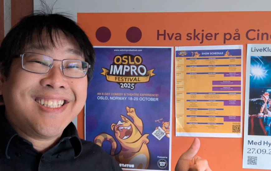 Smiling performer giving a thumbs-up beside a poster for the 2025 Oslo Improv Festival